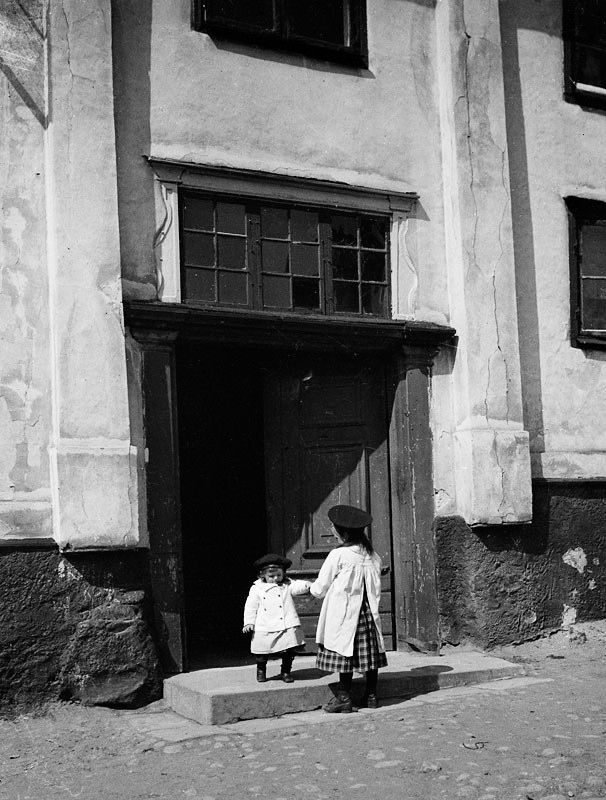 Två barn står vid porten på gårdssidan av Värmdögatan 63.